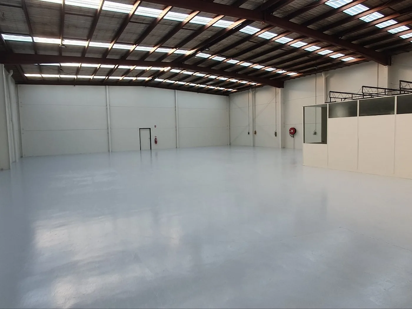 Finished commercial warehouse interior with clean floor, lighting and office area