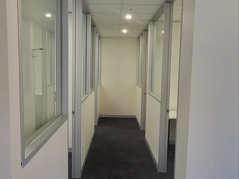 Completed office corridor with glazed partitions and dark carpet
