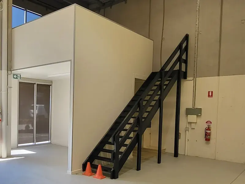 Completed enclosed office and mezzanine with staircase inside a commercial warehouse