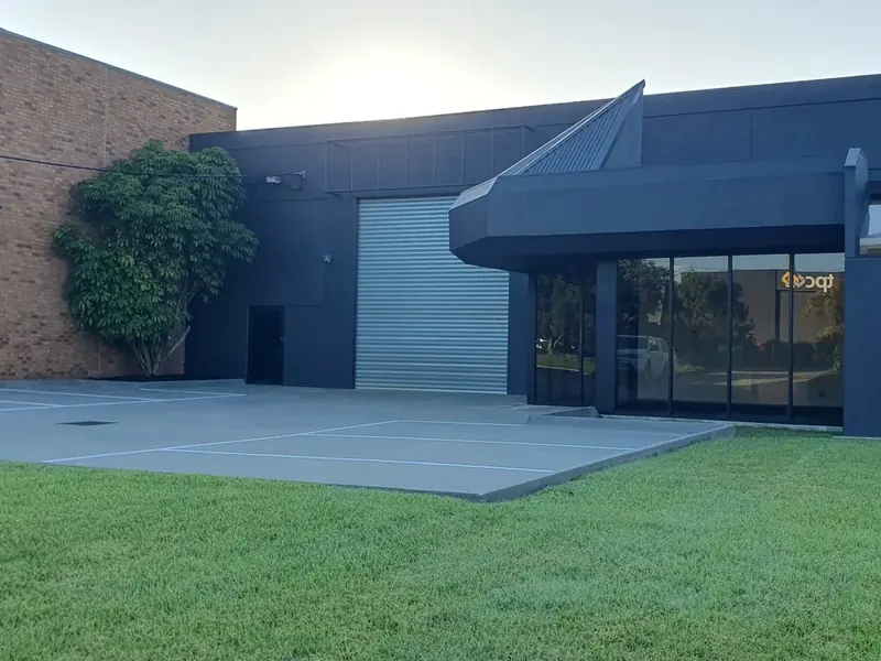 Rejuvenated commercial property exterior with dark façade, roller door and finished parking area